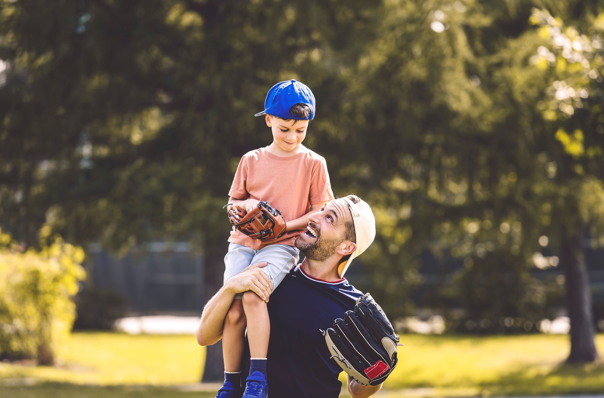 Father and son playing baseball in sunny day at public park